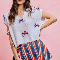 Off-white dolman sweater top with red, white, and blue ribbon bow accents