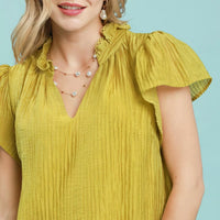 Close-up of Avocado textured mini dress with ruffled collar and V-neck