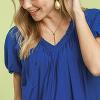 Blue V-neck mini shift dress close-up with gathered neckline and puff sleeves.