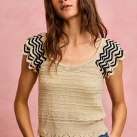 Oatmeal wavy textured knit top with flutter sleeves and black zigzag edges