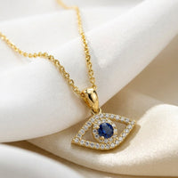 Gold evil eye elliptical necklace with blue stone pendant