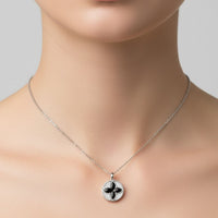Silver chain necklace with small round pendant featuring black four-leaf clover center
