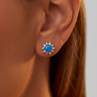 Gold sunflower blue opal stud earrings on ear with clear crystal accents