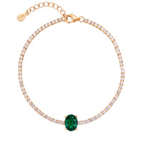 Gold tennis bracelet with oval emerald centerpiece and clear stones
