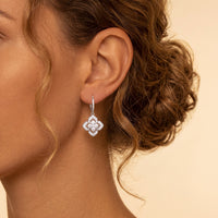 Silver CZ clover flower drop earrings, close-up side view on model