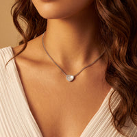 Silver heart mother-of-pearl necklace worn on model, small heart pendant on chain