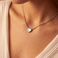 Silver heart mother-of-pearl necklace with small heart pendant on model neckline