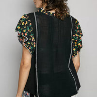 Black V-neck blouse with ruffle sleeves and floral print trim, back view