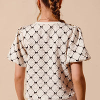 Ivory woven bubble sleeve top with black bow texture pattern, back view