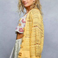 Yellow open-knit button cardigan from back view, long sleeves with ribbed waistband