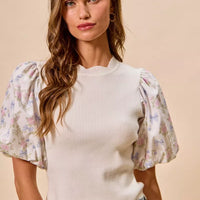 White sweater top featuring short floral puff sleeves with scalloped hem