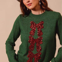 Hunter green Christmas sweater with red sequin bow ribbon detail at chest