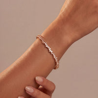 Rose gold ice cuff bangle with baguette-cut clear stones, close-up on wrist