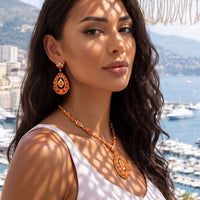 Gold-tone necklace with orange bead strand and large teardrop pendant with crystal halo