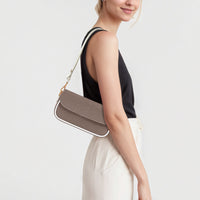 Brown leather shoulder bag with flap and gold chain strap worn at the side