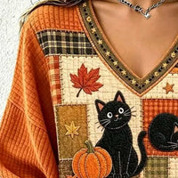 Orange V-neck sweater detail: black cat with pumpkin and leaf patchwork panel