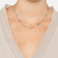 Silver chain necklace with round blue beads, worn at the collarbone