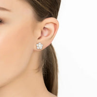 Silver-tone pearl stud earrings in flower design, worn on ear