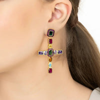 Gold cross gemstone earrings with multicolor stones, worn on ear