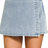 Light wash denim wrap-front skort with button closure and stitched hem