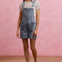 Light-wash denim romper with adjustable straps and front button placket