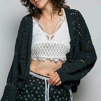 Black open-knit button cardigan worn open, long sleeves, crochet hole pattern