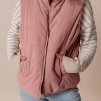 Dusty pink corduroy puffer vest with stand collar, full front zipper, and side pockets.