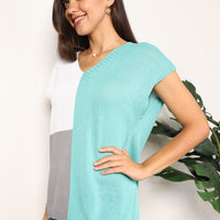 Side view of turquoise color-block V-neck knit top with white panel and short sleeves.