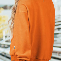 Orange mock neck sweatshirt back view, plain long sleeves and ribbed cuffs