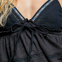 Close-up black cami neckline with embroidered trim and bow-tied front