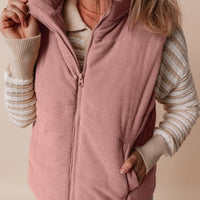 Dusty pink corduroy puffer vest with stand collar, zip front, and layered pocket detail.