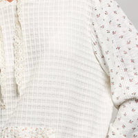 Cream knit hoodie close-up with floral-print sleeve and textured waffle fabric