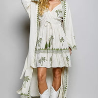 Natural palm tree print wrap dress with long draped sleeve overlay and tiered ruffle hem