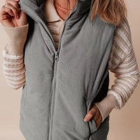 Gray corduroy stand-neck zipped puffer vest with full zipper and side pockets.