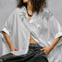 Ivory embroidered floral button-front shirt with open V-neck and flowing high-low hem