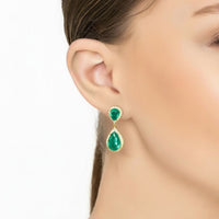 Emerald-green teardrop drop earrings on gold hooks, worn by model