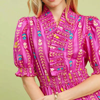 Close-up of pink smocked midi dress with ruffle collar, puff sleeves, and colorful print