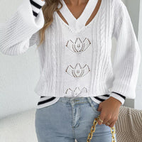 White cutout cable knit sweater with V-neck cutout and ribbed cuffs with black trim