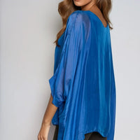 Royal blue silk blouse with round neck and batwing sleeves, angled side view drape.