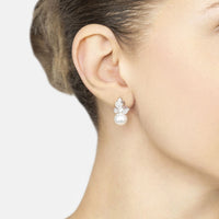 Butterfly stud-and-drop earrings with pearl drops on a model’s ear