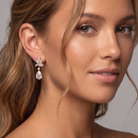 Gold-tone CZ drop earrings on model, pear-shaped stones with dangling drop