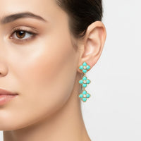 Turquoise enamel flower drop earrings on gold-tone hook, close-up on ear