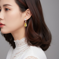 Small dangle earrings with yellow teardrop stones and clear top accents, gold tone