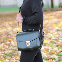 Leather satchel with front flap and metal buckle clasp, worn crossbody
