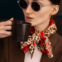 Woman wearing black round sunglasses with dark lenses and green temple accents