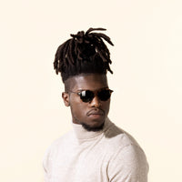 Tortoise sunglasses on person, dark lenses and rounded frames