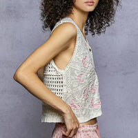 Cream sleeveless vest with pink floral embroidery and V-neck, front buttons.