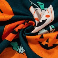 Close-up fabric with dark green and orange pumpkin print and jack-o'-lantern faces