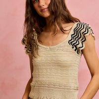 Oatmeal wavy textured knit top with flutter sleeves and black zigzag trim