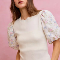 White ribbed sweater top with short floral puff sleeves and scalloped bottom edge